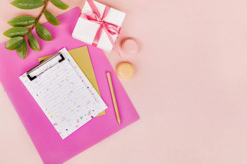 Feminine workspace with paper blank, pen, green branch, present box. Flat lay, top view.