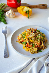 Bulgur with vegetables on a white plate on a kitchen table.