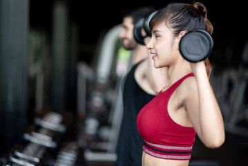 Fototapeta na wymiar Young healthy asian woman lifting dumbbells in the gym. Exercise, workout, muscle training, weight lifting, weight loss, heart rate practice and diet concept.