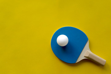 Table tennis rackets and white tennis ball lie on a bright multicolored background