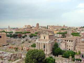 Fototapeta na wymiar Landscape of millennial columns and dilapidated majestic buildings of mighty Rome in the past, against the backdrop of modern areas under a cloudy sky on the horizon.
