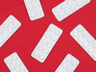 Pills in packages on a red background.