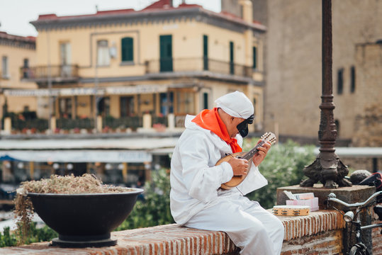 The mask of Pulcinella (Punchinello) plays the mandolin on the Naples promenade