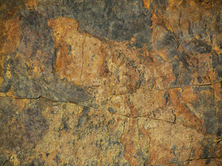 Black red grunge background. Fragment of a mountain close-up. Rusty rough stone surface.