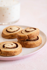 Cookies on a white plate with milk on a pink background.