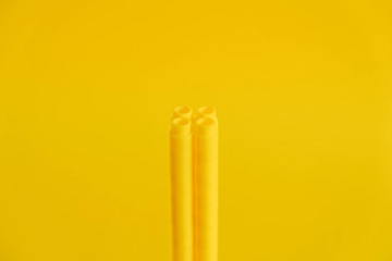 Yellow plastic building blocks in the shape of a tower on yellow background. Background of plastic details building blocks. Parts of bright small spare parts for toys. Copy, empty space for text