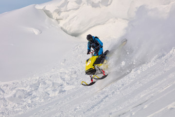 jump on a mountain snowmobile from a high ledge with the descent of a large avalanche. snowmobilers sports riding. Winter extreme. testing of a new model of mountain snowmobile, prototype 2021