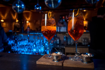two orange alcoholic coctail with ice on a wooden stand