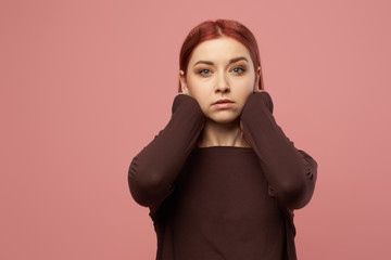 Serious young woman in burgundy sweater with hands behind her head