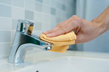 man cleaning the faucet of a sink
