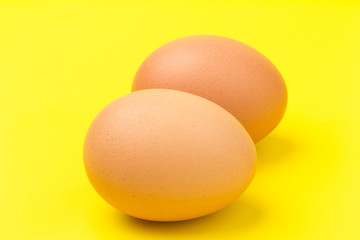 Brown eggs close up, isolated on yellow background. space for text