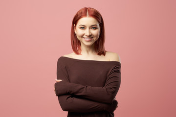 Young woman with closed eyes with arms crossed isolated on empty pink background