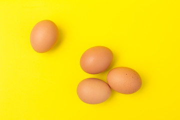 Brown eggs close up, isolated on yellow background. space for text