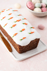 Tasty easter carrot sponge cake with cream and little carrots on pink background.