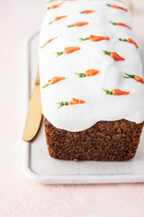 Tasty easter carrot sponge cake with cream and little carrots on pink background.