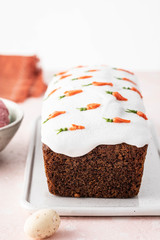 Tasty easter carrot sponge cake with cream and little carrots on pink background.