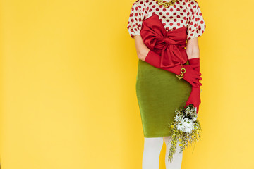 Cropped view of stylish elderly woman holding bouquet of wildflowers isolated on yellow