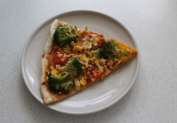 A portion of vegetable pizza with broccoli and cheese on a plate