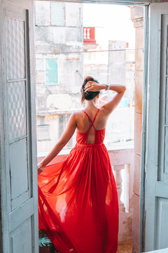 Young attractive woman in red dress on old balcony in apartment in Havana