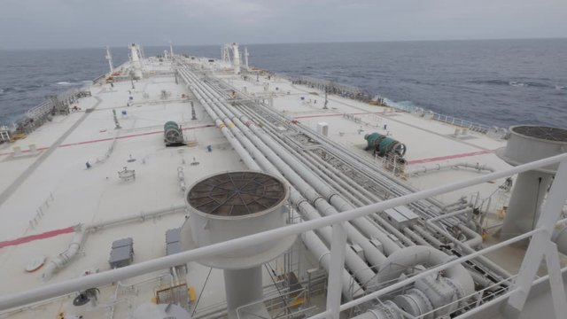 Deck of very large crude oil carrier in ocean, seamen on deck