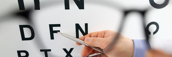 Silver pen pointing to letter in check table through eyeglasses