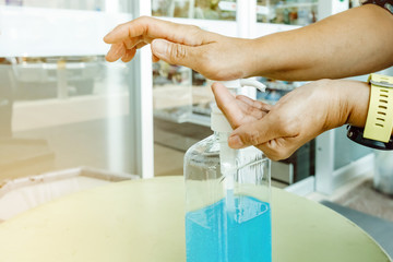 Woman uses her hand to press hand sanitizer bottle to clean her hand at wayside in the city. Concepts of Flu virus, Covid-19 (Coronavirus disease). Selective focus on alcohol gel bottle.