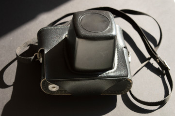 Vintage film photo camera on the dark sunny background. Combination of light and shadows