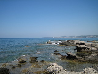 Weak waves gently wash the stones lying on the shallow bottom of the sea rocky shore in good weather.