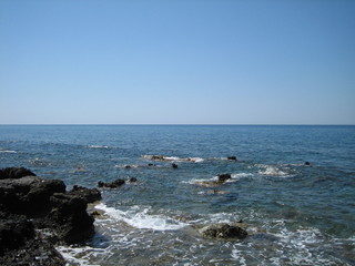 Weak waves gently wash the stones lying on the shallow bottom of the sea rocky shore in good weather.