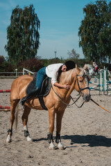 Portrait of young brunette woman in a white shirt and helmet on a horse