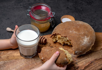 baking bread at home children's hands take a glass of milk bread on a gray background