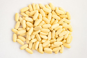 White yellow medicine pills supplement isolated on white background. Close up top view. Selective soft focus. Text copy space. Medicinal pharmaceutical concept