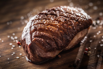 Roasted duck breast on wooden board with salt spices and rosemary