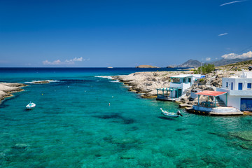 Fototapeta na wymiar Greece scenic island view - small harbor with fishing boats in crystal clear turquoise water, traditishional whitewashed house. MItakas village, Milos island, Greece.