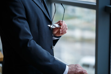 Adult male businessman, teacher, mentor looks out the large window of his office. Work in the...