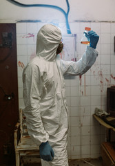 Scientist doctor biologist in hazmat suit and protective respiratory mask working in laboratory with test tubes searching vaccine against Coronavirus COVID-19