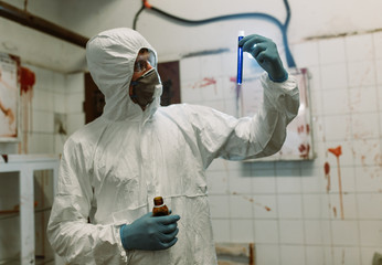 Scientist doctor biologist in hazmat suit and protective respiratory mask working in laboratory with test tubes searching vaccine against Coronavirus COVID-19