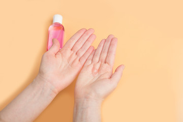 Disinfection of female hands with sanitizer gel against virus and bacteria on orange background. Coronavirus protection and healthcare concept. Safety rules during quarantine. Copy space for text