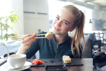 girl eats sushi and rolls in a restaurant / oriental cuisine, Japanese food, young model in a restaurant © kichigin19