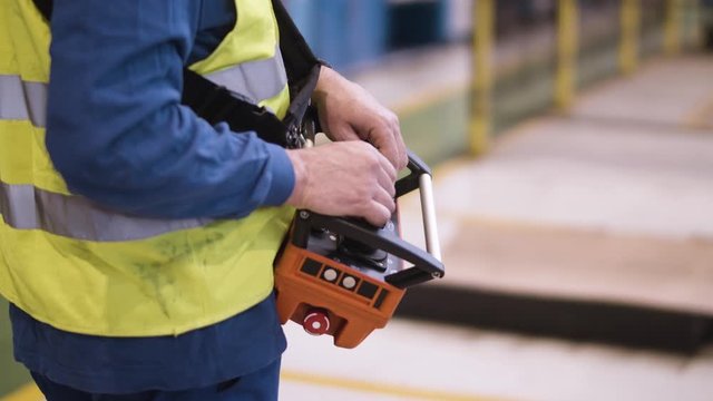 Close up of a worker inside a car manufacturing plant using a machinery handheld controller