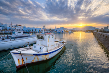 Fototapeta premium Old fishing boat in port of Naousa on sunset with dramatic sky. Paros lsland, Greece