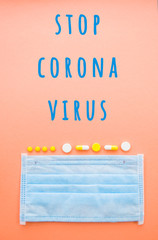 A syringe with a needle and a blue face mask on orange color background. Stop coronavirus concept. Protect yourself.