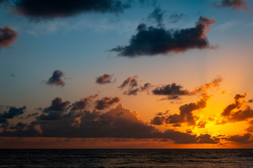 Fototapeta na wymiar Shocking sunrise at the edge of the sea. Calm sunrise. The gold painted sky and dark clouds am...