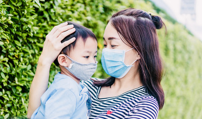Coronavirus and Air pollution pm2.5 concept.Little chinese boy and mother wearing protection face mask for protect from pm2.5 covid-19 virus at home.Covid-19 coronavirus and pandemic virus symptoms.