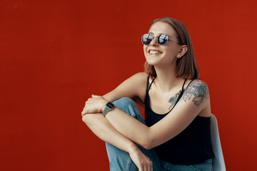 Young girl sitting on a white chair near the red wall