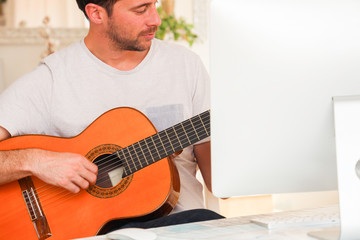 Obraz premium Model learning online how to play guitar by himself.