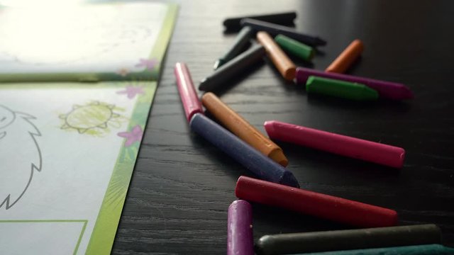 A three-year-old child chooses colored crayons to paint