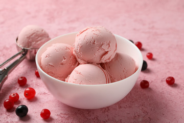 Bowl with ice cream and berries on pink background, close up