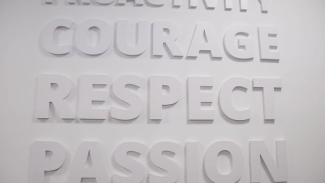 Close up of an inspirational text wall inside a corporate building. Proactivity, courage, respect, passion. Business values