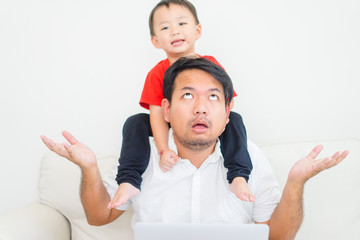 Fototapeta na wymiar Crazy father with his son at home.Covid-19 Coronavirus pandemic Quarantine and Working from home concept.Asian father working from home but his son want to play with daddy.Horrible situation at home.